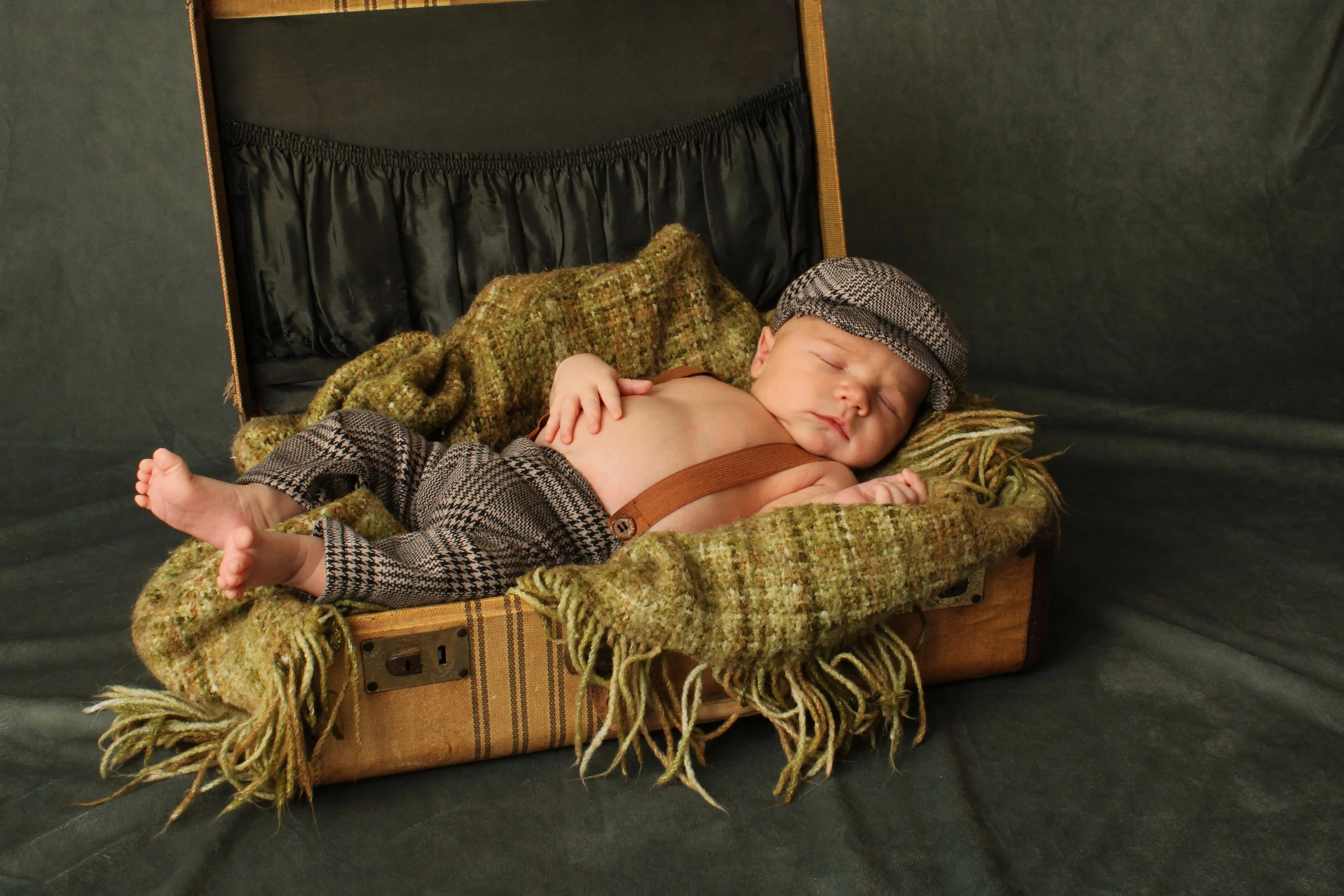 Newborn baby boy sleeping inside a vintage suitcase prop during a styled newborn photography session on Long Island